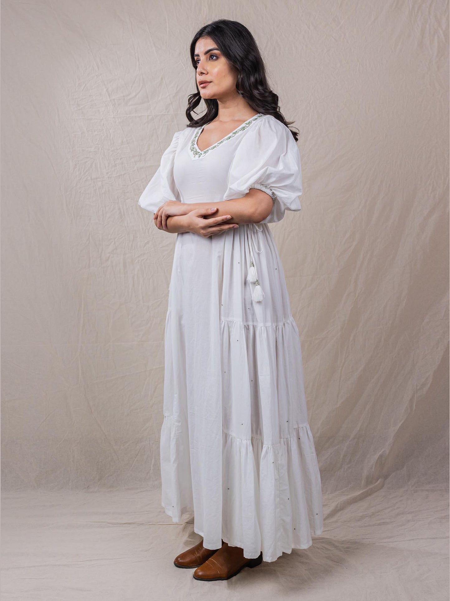 a line white colour dress in pure cotton. with tiers and gathers on the side. hand embroidered V neckline with other fine handwork details at the back of the dress.