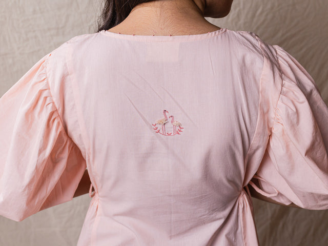 a line rose pink colour dress in pure cotton. with tiers and gathers on the side. hand embroidered V neckline with other fine handwork details at the back of the dress.