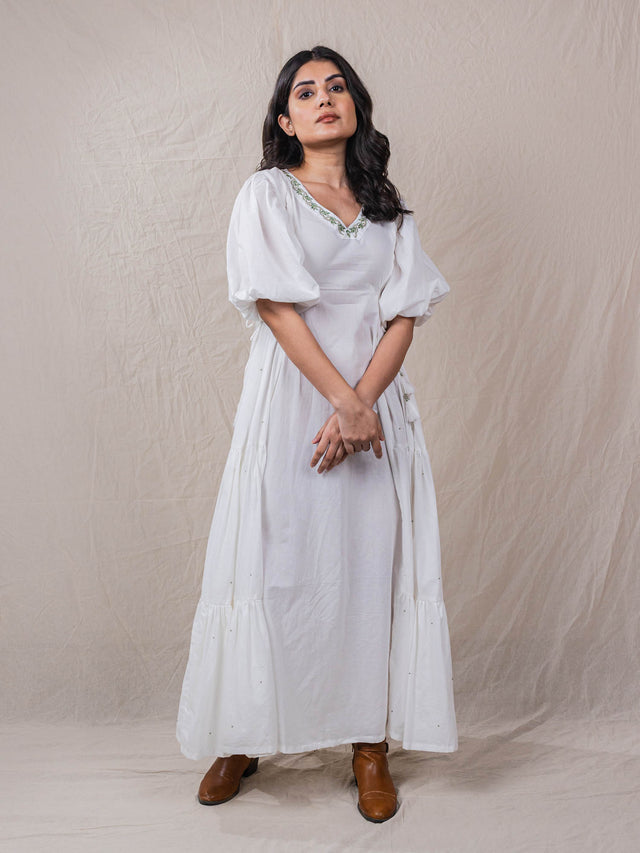a line white colour dress in pure cotton. with tiers and gathers on the side. hand embroidered V neckline with other fine handwork details at the back of the dress.