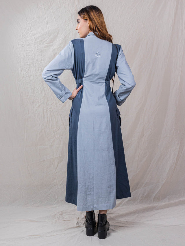 Waddle is a trench dress, cinched around waist, with pockets, embroidered back, power shoulders, button down, detail of buttons on sleeves