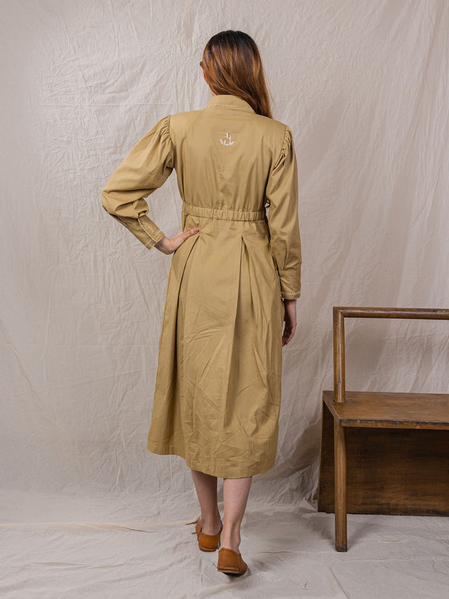 trench dress, cinched around waist, with pockets, puff sleeves with power shoulders, overlap front, detail of buttons on sleeves with embroidery